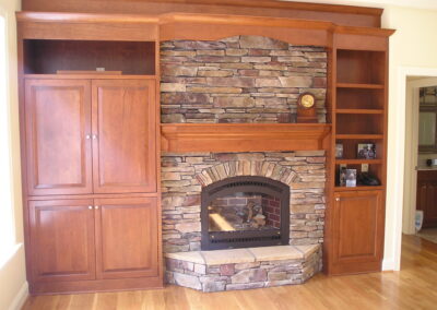 new gas fireplace in living room with stone surround and wooden mantel
