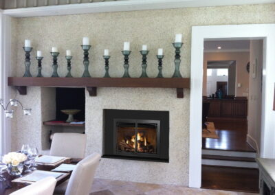 new gas fireplace in living room ith stone surround and wooden mantel