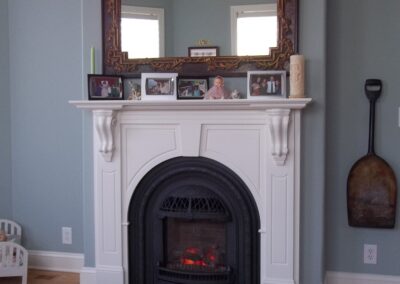 new gas fireplace in living room with white wood surround and mantel