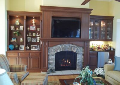 new gas fireplace in living room with stone surround and wooden mantel