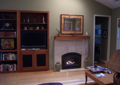 new gas fireplace in living room with stone surround and wood mantel