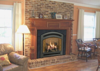 new gas fireplace in living room with brick surround and wooden mantel