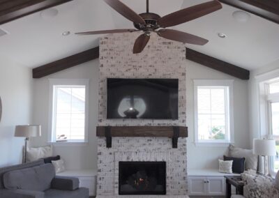new gas fireplace in living room with white brick surround and wooden mantel