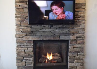 new fireplace with stone surround, gas, and tv mounted
