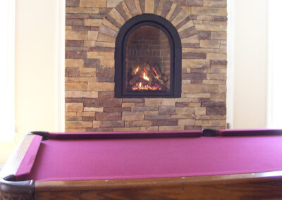 gas fireplace next to pool table with stone surround