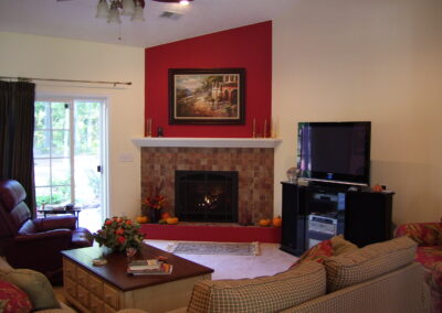 new gas fireplace with stone surround, white wood mantel, and red painted wall