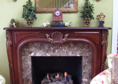 gas fireplace with logs, stone surround and dark wood mantel